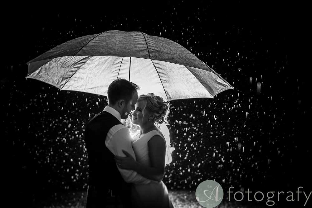wedding couple under umbrella during the rain at hopetoun house